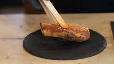 Siyah eldiven giyen şef hazır pirzolaları servis panosuna koyuyor. Kapat..