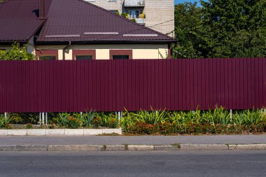 Bir yerleşim yerinin önündeki kırmızı metal çitle çevrili. Profilli metalin dokusu.