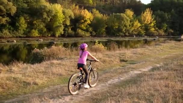 Una Niña Pequeña Monta Una Bicicleta Casco Protector Cerca Del — Vídeos de Stock