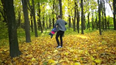 Genç bir baba kızını daireler çizerek döndürüyor, bağ kuruyor, oynuyor, güneşli ve aydınlık bir günde doğada eğleniyor. Ebeveynlik, yaşam tarzı, ebeveynlik, çocukluk ve aile hayatı kavramı.
