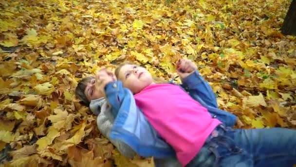 Мать Дочь Лежат Желтых Листьях Играют Осеннем Парке Медленное Движение — стоковое видео