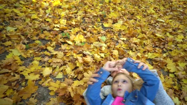Μητέρα Και Κόρη Ξαπλωμένες Κίτρινα Φύλλα Παίζουν Στο Φθινοπωρινό Πάρκο — Αρχείο Βίντεο
