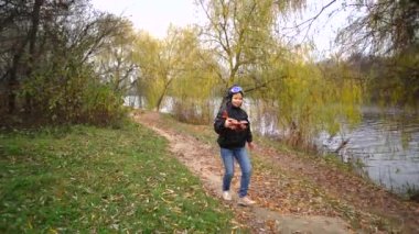 Autumn Park 'ın arka planında oyuncak bir uçakla gölde oynayan mutlu çocuk. Pilot kasklı gözlüklü bir kız.. 