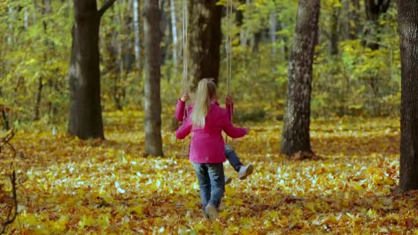 Twee Kleine Meisjes Spelen Met Touwschommel Zwaaien Elkaar Het Najaarspark — Stockvideo