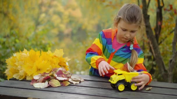 Маленька Дівчинка Грає Іграшковою Машиною Осінній День Прибирання Справжнього Листя — стокове відео