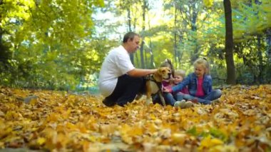 Mutlu aile güz parkında bir Beagle köpeğiyle yürüyor. Çocukların köpeği..