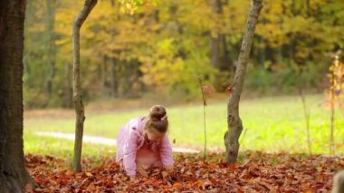 Küçük kız parka sonbahar yaprakları fırlatıyor. Sonbahar Parkı 'nda oynayan çocuk. Düşen yapraklar. Sonbaharda açık hava eğlencesi.