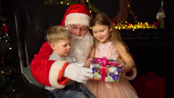 Αγοράκι Και Κορίτσι Κάθονται Στην Αγκαλιά Του Βασίλη Χριστουγεννιάτικο Δώρο — Αρχείο Βίντεο
