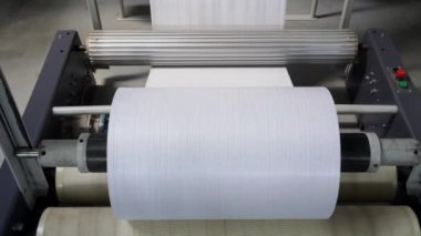 Poşet üretimi için ortaya çıkan polipropilen kol büyük makaralara sarılmış. dokuma polipropilen ipliklerinin kollarını sarmak için davul. PP çanta üretim hattı