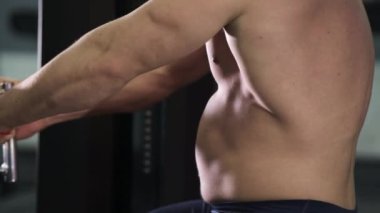 Kaslı bir adam spor salonunda kauçukla ağırlık kaldırıyor. Kapat..