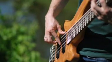 Genç adam doğanın arka planında elektro gitar çalar. Kapat..