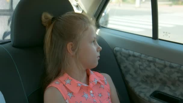 小さな女の子は 車の中で退屈 窓から窓の外を見る 通りの反射 — ストック動画