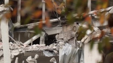 Yüksek erişimli kazıcı kıskaçları ev duvarını yıkıyor. Kazıcının hidrolik kolu bir eve çarpıyor ve yıkıyor.