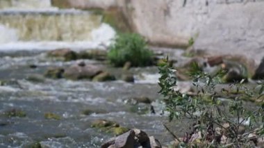 Güneşli bir günde küçük bir baraj manzarası. Suyun aktığı küçük bir baraj. Köpüklü çizgiler ve desenler olarak görülüyor. Yavaş çekim 100fps