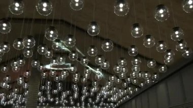 Tavanın altında bir sürü yuvarlak avize ve lamba var. Karanlık modaya uygun iç mekanlarda parlayan lambalar, aydınlatma ve iç mekan konsepti..