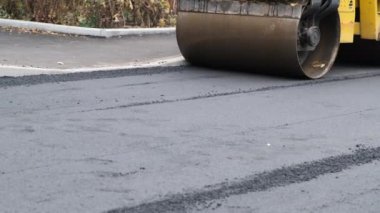 Çok katlı bir evin bahçesinde küçük bir pist asfaltı yuvarlıyor. Kapat..