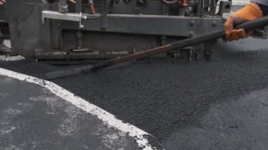 Bir işçi asfalt ile paspası bir arada tutar. Kapat.