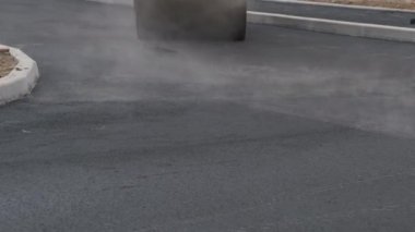 Çok katlı bir evin bahçesinde küçük bir pist asfaltı yuvarlıyor. Kapat..
