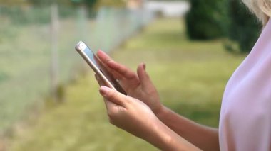 Kız elleri akıllı telefona dokunuyor. Parlak arkaplan, yakın plan.