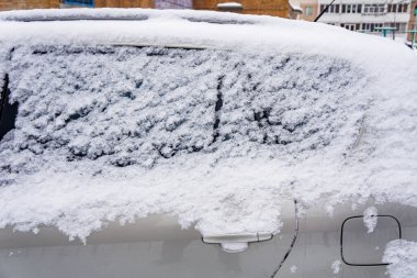 Şiddetli kar yağışı sonrası avlu. Kalın kar tabakasıyla kaplı araba. Arabanın sol tarafı karla kaplı.