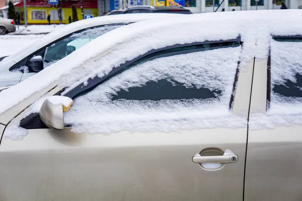 Courtyard after heavy snowfall. The car, covered with thick layer of snow. Left side of  car covered with snow