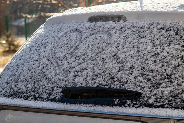 Car back window covered with snow. After snowfall