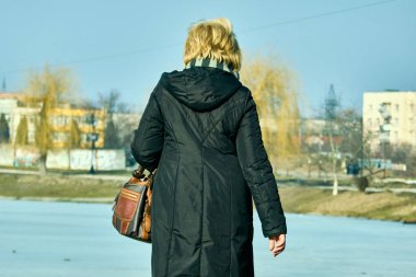 Bir kadın kış gölün etrafında yürür