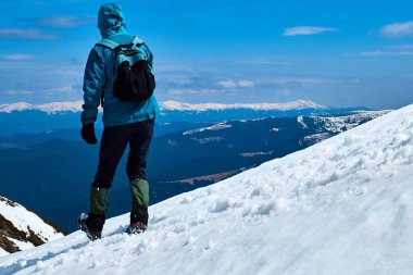 turist dağdan karla kaplı zirvelere bakarak iner