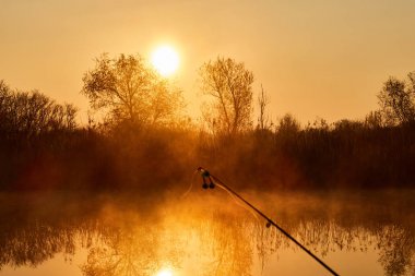 Gölde sisli gün doğumunda olta yakın çekim , Göl üzerinde gün doğumu su yüzeyine yansıyan
