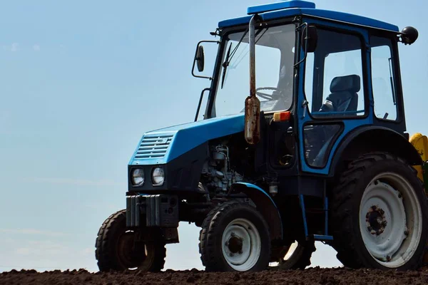 Un tractor en el campo planta patatas y cultiva el suelo, plantando patatas con un pequeño tractor —  Fotos de Stock