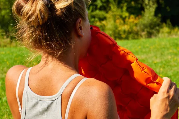 girl inflates sleeping mat in nature