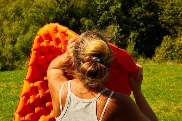 girl inflates sleeping mat in nature