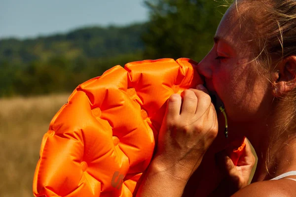 girl inflates sleeping mat in nature