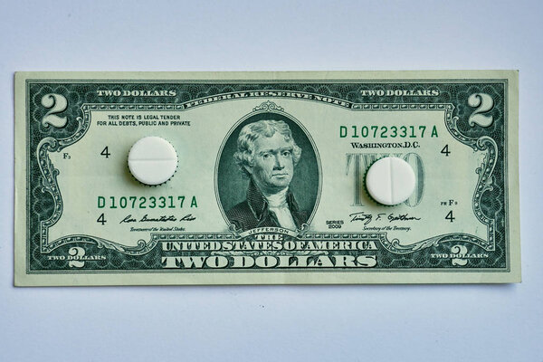 Pills on dollar money isolated on white background. Medicine expenses , one way road