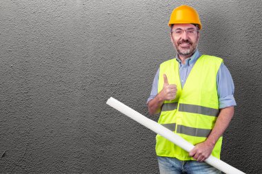 İnşaat işçisi holding blueprint gri bir duvara