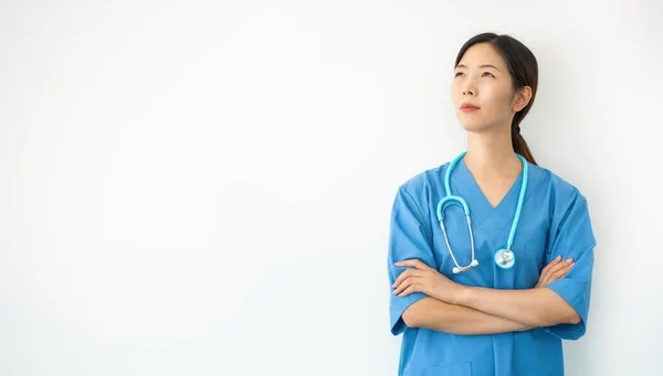 青い制服を着たアジア系女性の医者は白人の背景で隔離された若い医療従事者が上を向いている — ストック写真