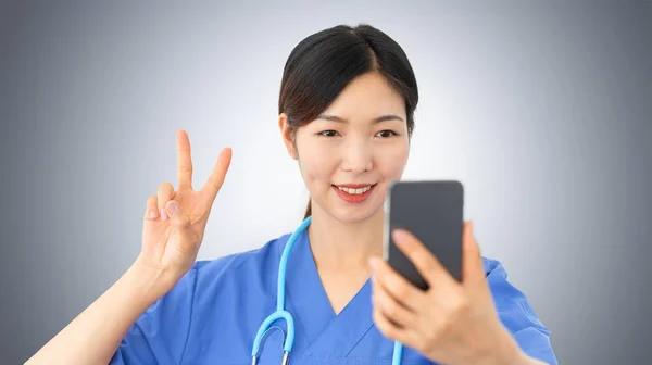 Piękny Azjatycki Lekarz Robi Selfie Gestykulując Znak Zwycięstwa Jej Palcami — Zdjęcie stockowe