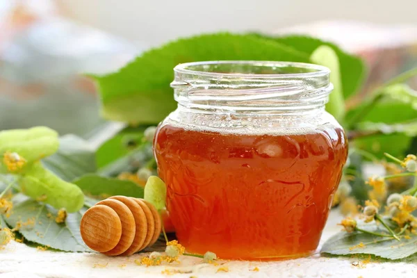 Linden honey in glass jar and linden flowers