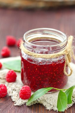 Ahududu reçeli bir jur ve ahşap masa üzerinde taze çilek