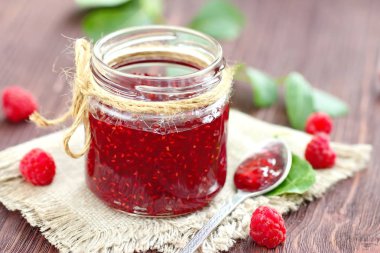 Ahududu reçeli bir jur ve ahşap masa üzerinde taze çilek