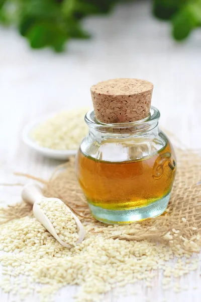 Sesame oil in glass and sesame seeds on the table