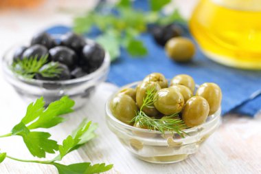 Cam kase ve zeytinyağı bir tabloda yeşil ve siyah zeytin