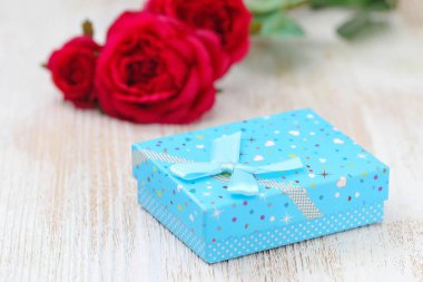 Taze kırmızı güller ve hediye kutusu ahşap masa üzerinde. St Sevgililer günü kavramı.