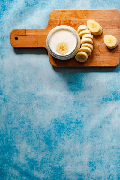 Sliced banana with banana yogurt on blue background