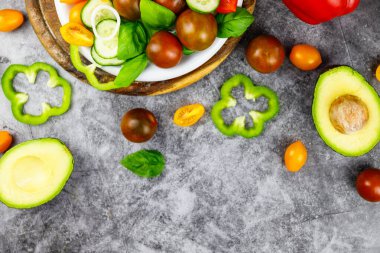 Domatesli lezzetli iştah açıcı salata, salatalık, gri taşlı arka planda biber kasesi. Yukarıdan görüntüle. 