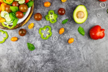 Domatesli lezzetli iştah açıcı salata, salatalık, gri taşlı arka planda biber kasesi. Yukarıdan görüntüle. 