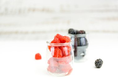 Bahçe meyveleri, ahududu ve bektaşi üzümlü cam şişeler içinde ahşap arka planda. Sağlıklı gıda konsepti. Okul defterleri için resim.