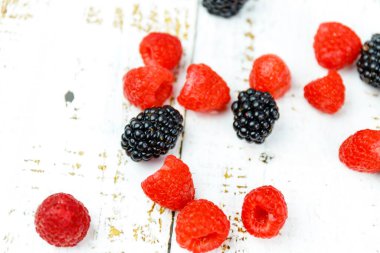 Taze böğürtlen çeşitleri. Ahşap yüzeyde ahududu ve Bektaşi üzümü. Yaz zamanı taze atıştırmalık. Okul malzemeleri için mükemmel bir görüntü..