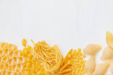 Beyaz ahşap arka planda çeşitli pişmemiş makarna. Üst Manzara. Restoran için İtalyan makarnası, metin için yer var..