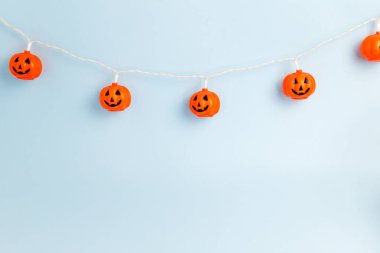 Açık mavi arka planda gülümseyen Cadılar Bayramı balkabağı